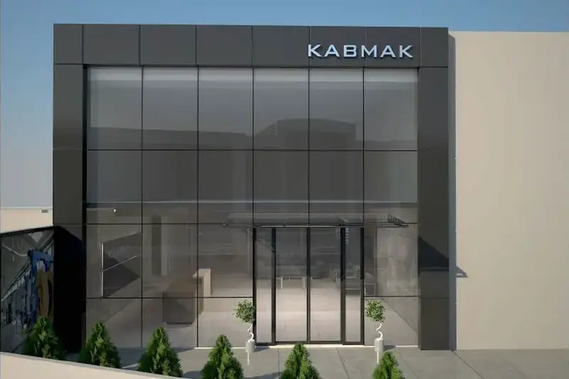 Kabmak fabrikasının giriş cephesi, koyu çerçeveli cam cephe ve çift kanatlı cam kapı