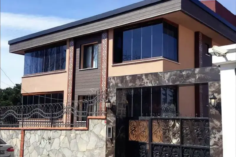 Villa Başdemir dış cephesi, taş kaplı bahçe duvarı, ferforje kapı ve ahşap desenli kaplama