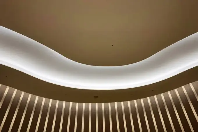 Temsilî görsel, dalga biçimli gizli ışıklı alçı tavan ve altında ahşap lamel
